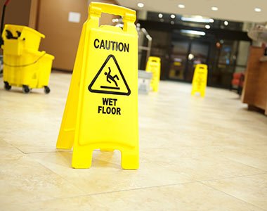 Yellow "caution: wet floor" signs placed on a tiled floor in an indoor setting by a San Francisco maid service.