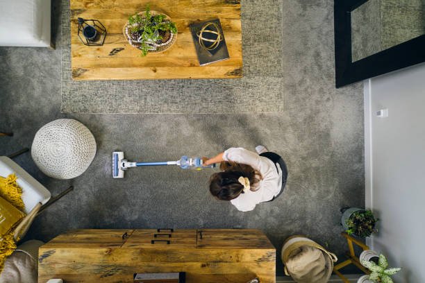 Top-down view of a person from a house cleaning company vacuuming a modern living room.